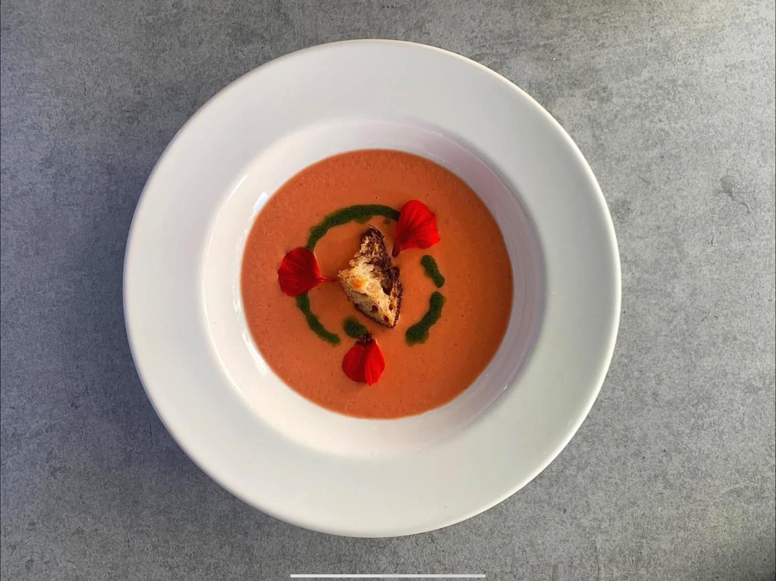 Chilled tomato soup with a crouton, basil oil and edible flowers